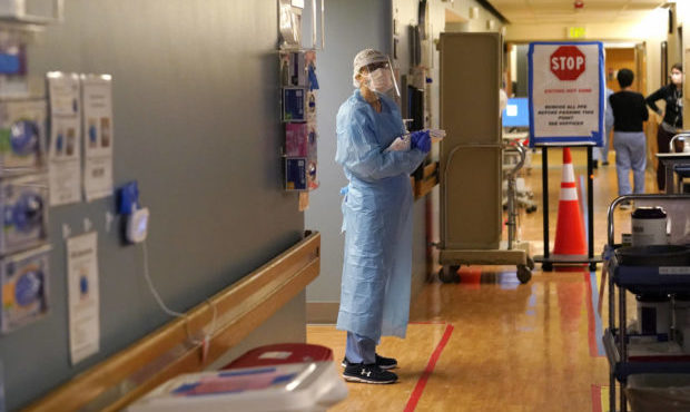 In this Jan. 26, 2021, file photo, registered nurse Diane Miller stands in the "hot zone," defined by red tape on the floor, as she waits to exchange equipment with a colleague who will remain on the other side of the tape in the COVID acute care unit at UW Medical Center-Montlake in Seattle. (AP Photo/Elaine Thompson, File)