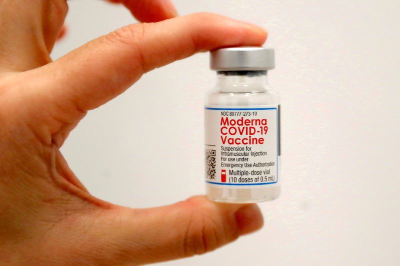 Close up of hand holding bottle of Moderna COVID-19 vaccube
