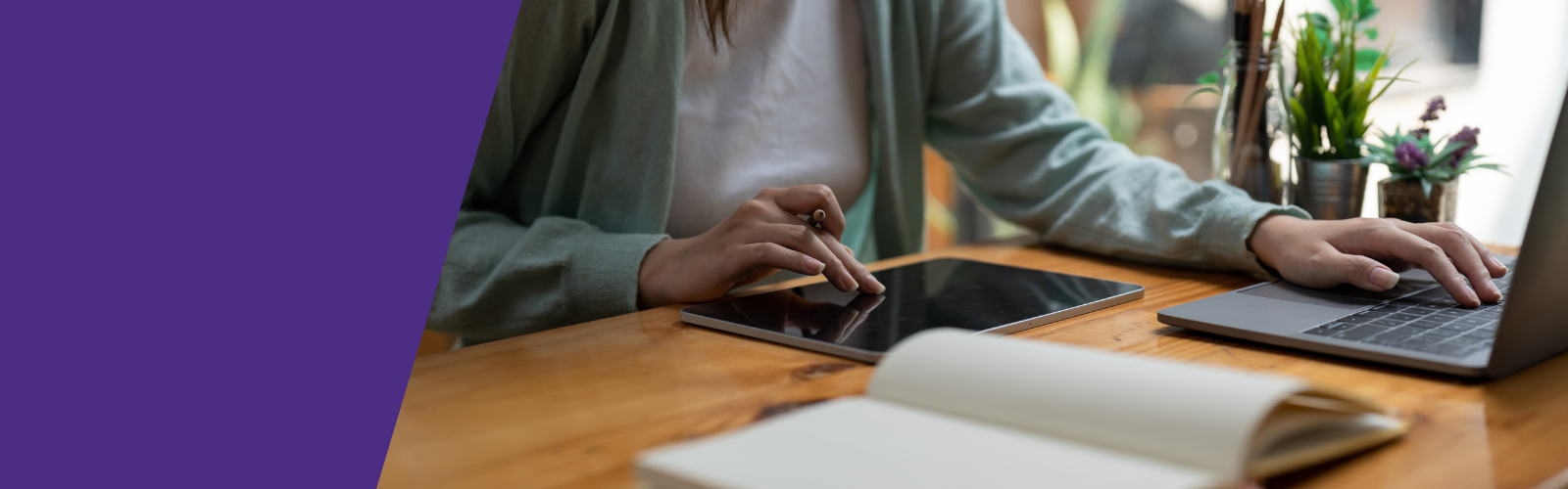Woman working at a desk on a tablet and laptop
