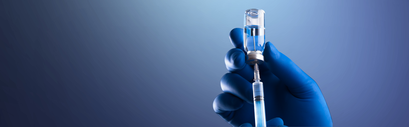 Photo of medical worker wearing blue glove holding vaccine and syringe