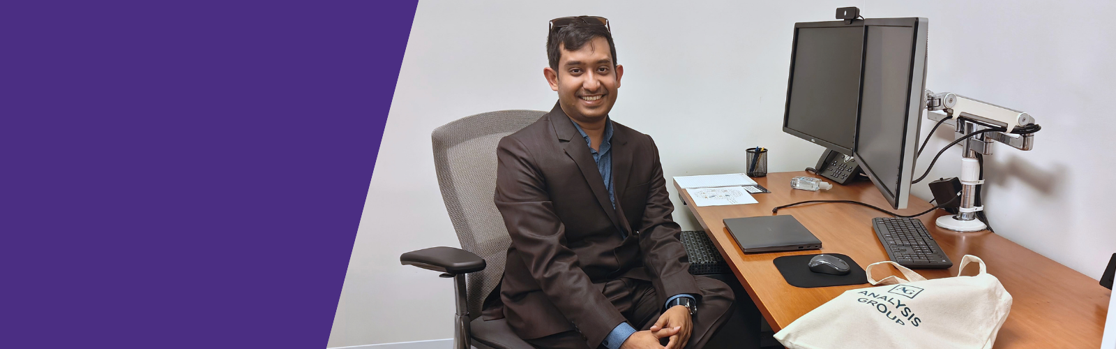 Awan Afiaz sitting at work desk at Analysis Group internship work site