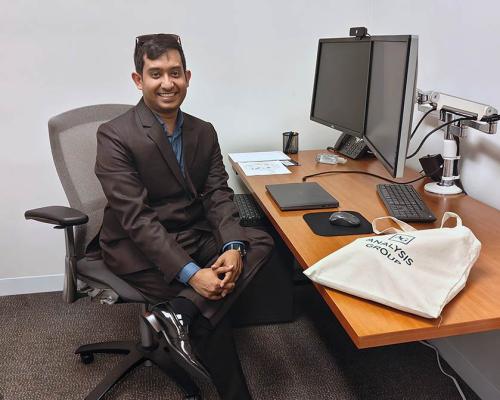 Awan Afiaz sitting at desk at Analysis Group work site
