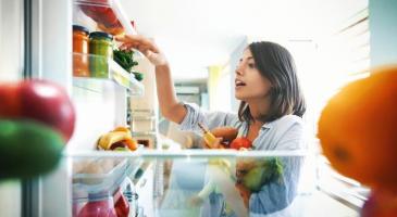 Woman gathering fruits and vegetables from fridge