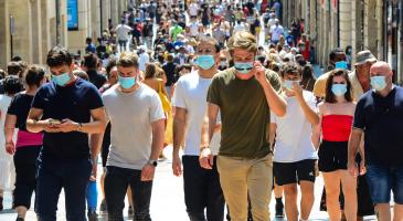 Masked people walking down a crowded street