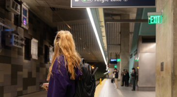 Photo of lone student waiting on light rail platform