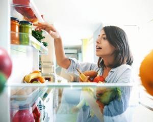 Woman gathering fruits and vegetables from fridge