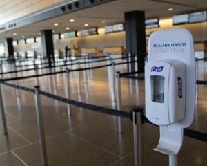 Photo of empty airport check-in lines with hand sanitizer dispenser stand at front