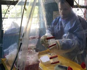 CDC biologist works on mobile biocontainment unit wearing protective gear