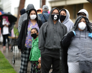 People wait in line outside food bank, wearing protective masks