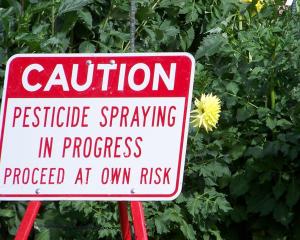 Sign that says: Caution: Pesticide spraying in progress. Proceed at own risk