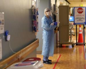 In this Jan. 26, 2021, file photo, registered nurse Diane Miller stands in the "hot zone," defined by red tape on the floor, as she waits to exchange equipment with a colleague who will remain on the other side of the tape in the COVID acute care unit at UW Medical Center-Montlake in Seattle. (AP Photo/Elaine Thompson, File)