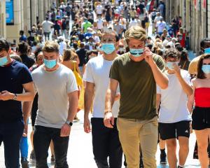 Masked people walking down a crowded street
