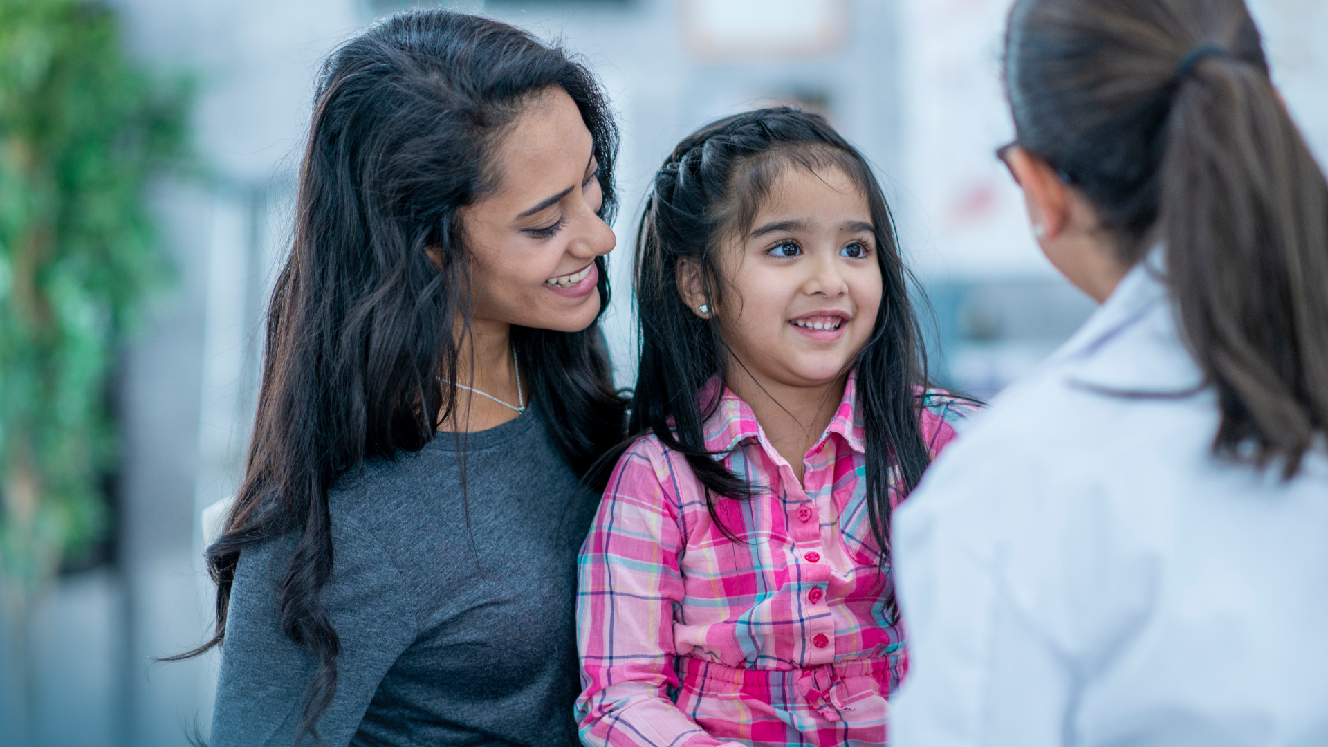 Photo of clinician speaking with woman and child in a medical office