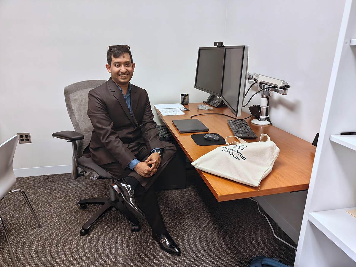 Awan Afiaz sitting at desk at intership site, Analysis Group